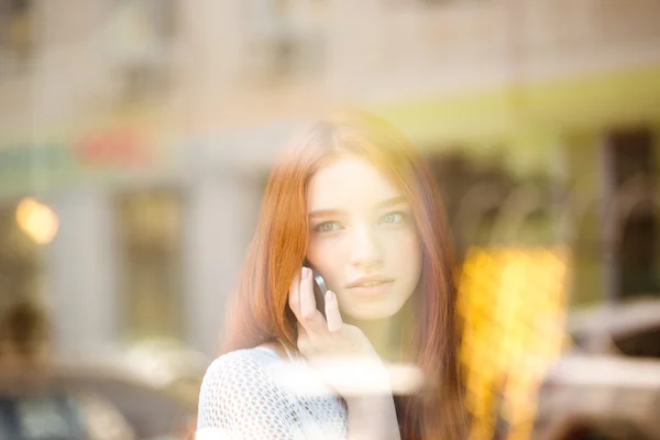 Woman talking on the phone and looking in window — Stock fotografie