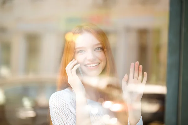 Mulher falando ao telefone e olhando para a janela — Fotografia de Stock