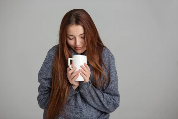 Hermosa joven sonriente sintiéndose fría y bebiendo té caliente —  Fotos de Stock