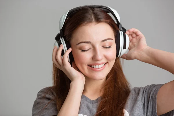 Smiling lovely young woman listening to music using headphones — Stockfoto