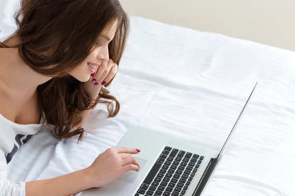 Top view of smiling beautiful young female typing on laptop — 图库照片