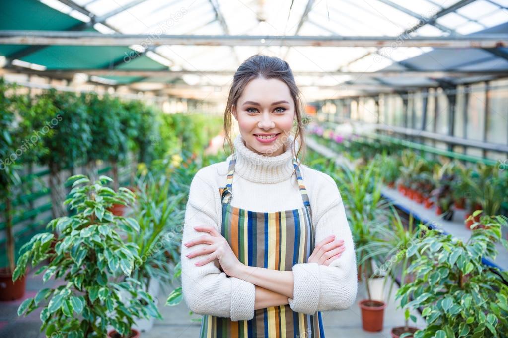 Beautiful happy young woman gardener in colorful striped apron