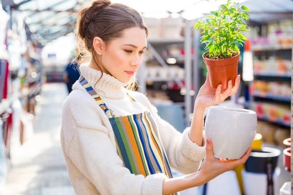 Thoughtful woman gardener choosing new pot in store — Stock Photo, Image