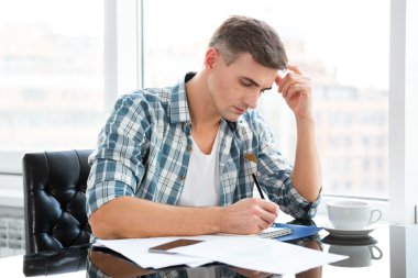 Handsome thoughtful man sitting and drawing in office 