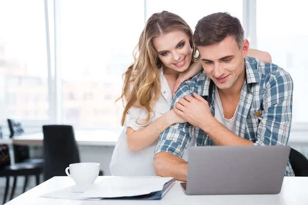 Couple heureux en utilisant un ordinateur portable ensemble assis à la table — Photo