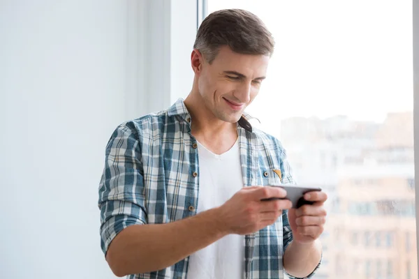 Guapo sonriente macho usando smartphone — Foto de Stock