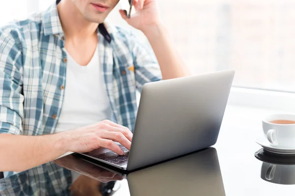 Człowiek za pomocą laptopa i rozmowy na telefon komórkowy — Zdjęcie stockowe