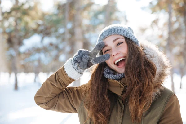 Woman showing peace sign in winter park — Stock Photo, Image