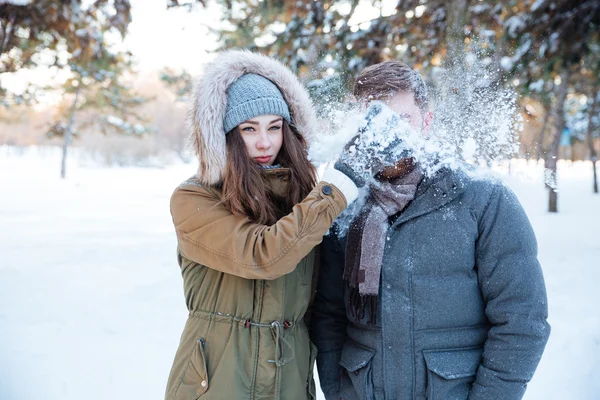Mulher divertida thowing bola de neve em seu rosto namorado — Fotografia de Stock