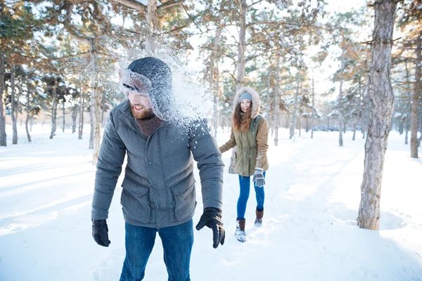 Mulher alegre thowing bolas de neve em homem bonito — Fotografia de Stock