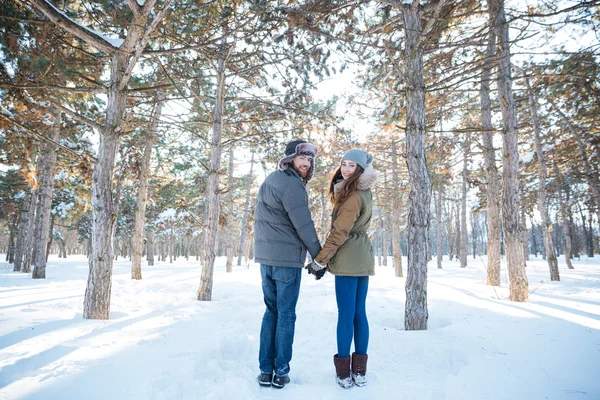 Щаслива молода пара дивиться назад в зимовий парк — стокове фото