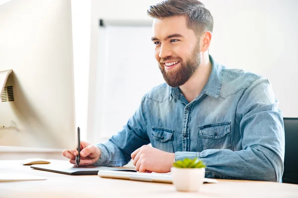 Feliz diseñador masculino sentado y dibujando en la tableta gráfica — Foto de Stock