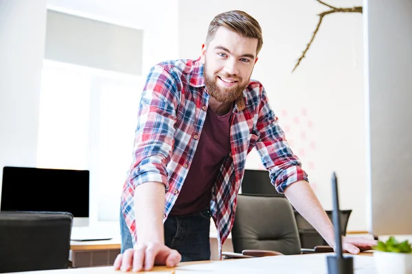 Glimlachend zeker jonge man met baard staan in kantoor — Stockfoto