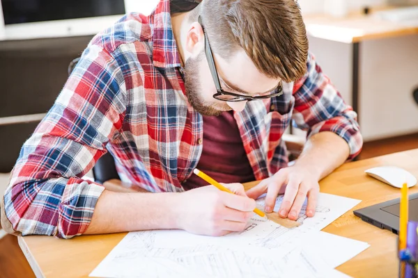 Estudiante trabajador serio sentado en el escritorio y dibujo plano —  Fotos de Stock