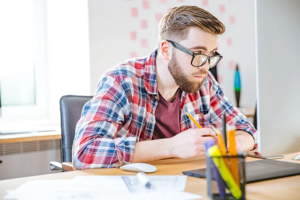 Allvarlig man sitter på arbetsplatsen och tittar över glasögon — Stockfoto