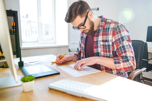 Porträtt av unga manliga designer sitter och gör blueprint — Stockfoto