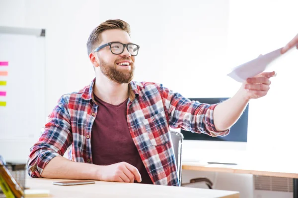 Cheerful man siting on workplace and receiving documents — Stock Photo, Image