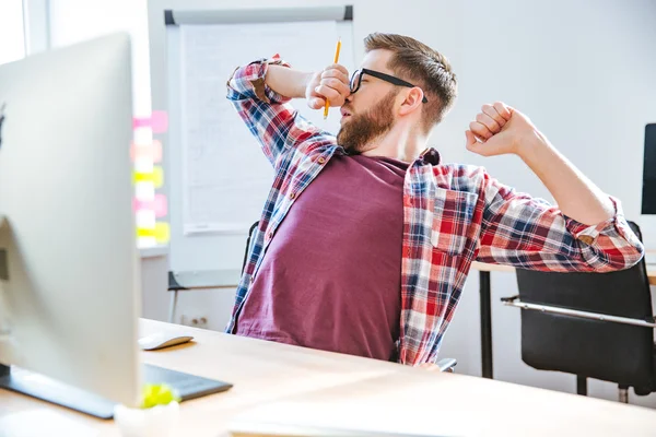 Fatigué beau homme étirement et bâillement sur le lieu de travail — Photo