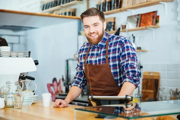 Jovem barista alegre e bonito com barba trabalhando no café — Fotografia de Stock