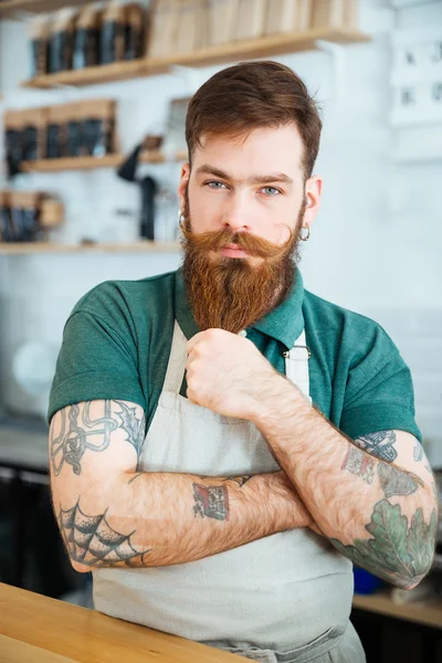Atraktivní muž barista postavení a dotýká bradě — Stock fotografie