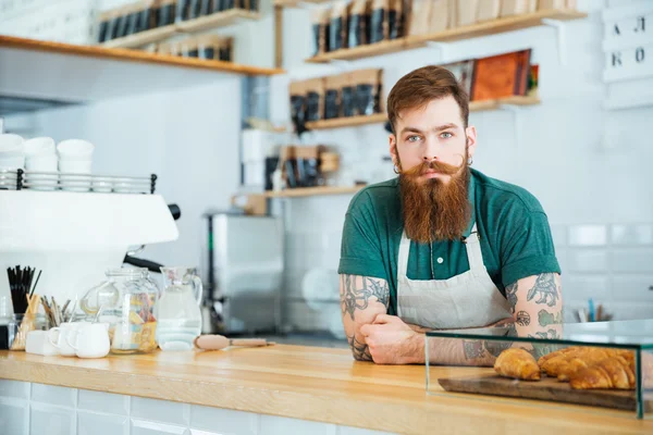 Retrato de un barista barbudo de pie en una cafetería —  Fotos de Stock