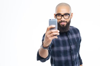 Handsome african man with beard taking selfie using smartphone clipart