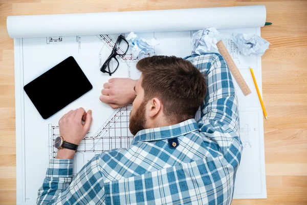 Agotado joven arquitecto barbudo durmiendo en el lugar de trabajo — Foto de Stock