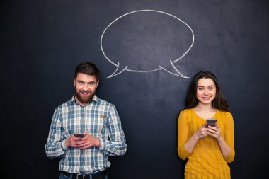 Mutlu çift cep telefonu konuşma balonu ile kara tahta üzerinde kullanma 