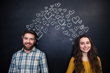 Mutlu çift ayakta çizilen kalpler ile kara tahta arka plan üzerinde 