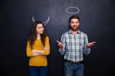 Mutlu çift şeytan ve melek yazı tahtası üzerinde artalanda çalışır