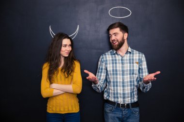 Çift taklit şeytan ve melek kara tahta arka plan üzerinde gülümseyen