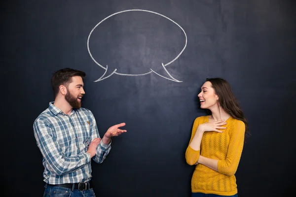 Pareja feliz hablando sobre el fondo de pizarra con el diálogo dibujado — Foto de Stock