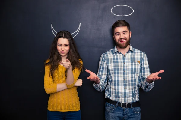 Belo casal de pé sobre quadro negro com chifres desenhados e halo — Fotografia de Stock