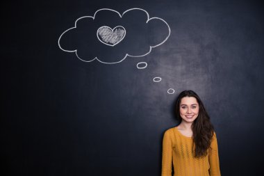 Woman thinking about love and standing with blackboard behind her