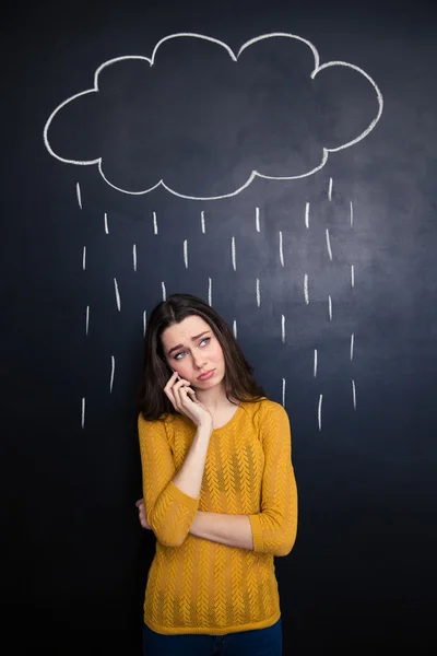 Disappointed woman talking on cellphone under rain drawn at blackboard — Stok fotoğraf