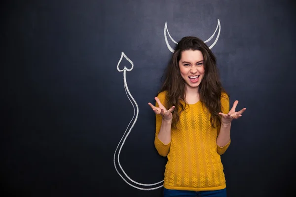 Funny woman playing role of devil standing over chalkboard — Stok fotoğraf