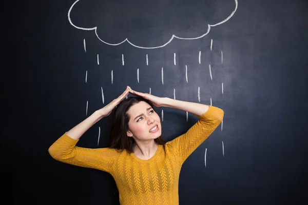 Annoyed woman covering head from rain drawn on chalkboard background — Stok fotoğraf