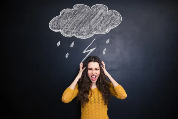 Angry young woman screaming over blackboard behind her — Stock Photo, Image