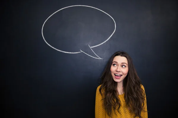 Cheerful woman smiling over blackboard with empty speech bubble — Zdjęcie stockowe