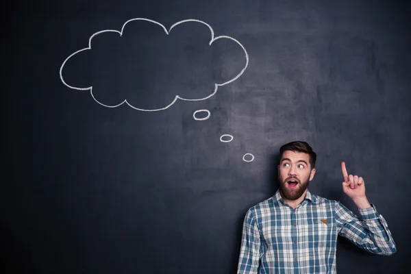 Inspired man pointing up and having an idea over blackboard — Stock Photo, Image