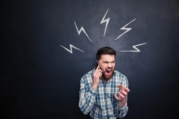 Homem louco usando telefone celular e gritando sobre fundo blackboard — Fotografia de Stock