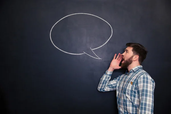 Beau homme criant contre fond de tableau avec bulle de discours dessinée — Photo