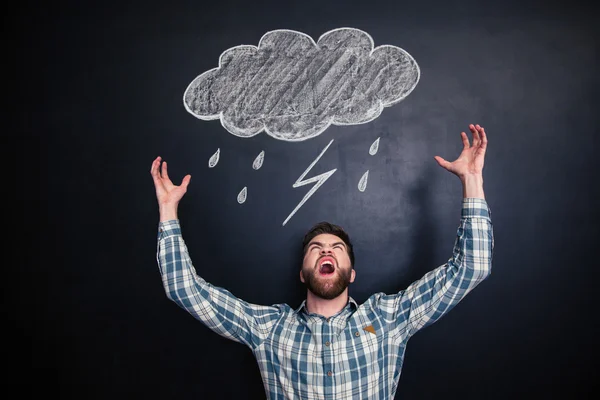 Wütender Mann steht und schreit mit gezogenem Regenschirm über Tafel — Stockfoto