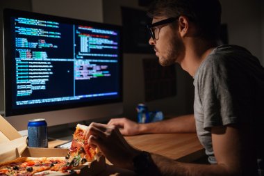 Concentrated software developer eating pizza and coding 
