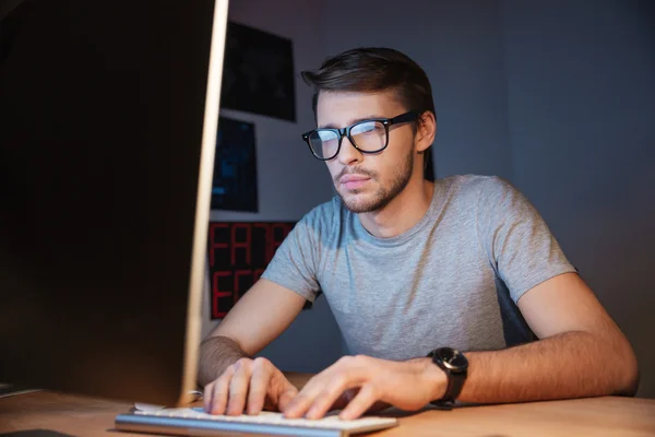 Koncentrerad allvarlig man i glas använder datorn hemma — Stockfoto