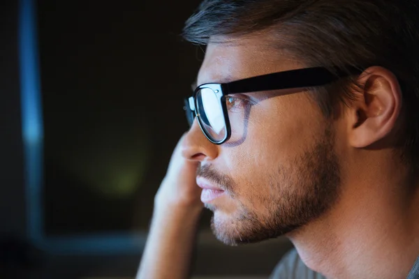 Thoughtful young man with bristle in glasses sitting and thinking — Stock Photo, Image