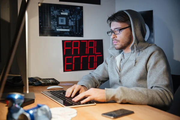 Schöner Mann im Sweatshirt mit Kapuze tippt auf Computertastatur — Stockfoto