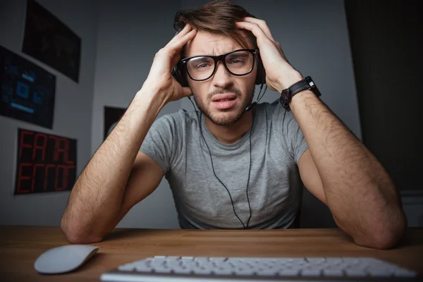 Hombre sentado con las manos en la cabeza delante de la computadora —  Fotos de Stock