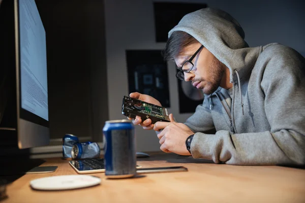 Серийный мужчина смотрит на сломанный жесткий диск дома — стоковое фото