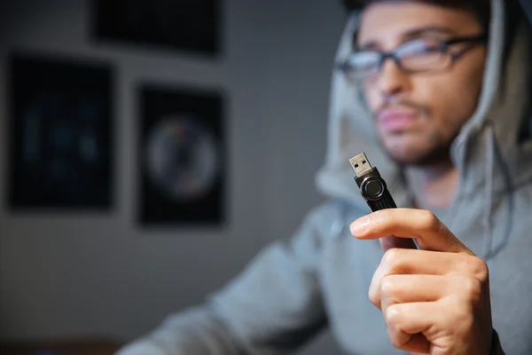 Bonito homem de óculos sentado e segurando cabo usb — Fotografia de Stock